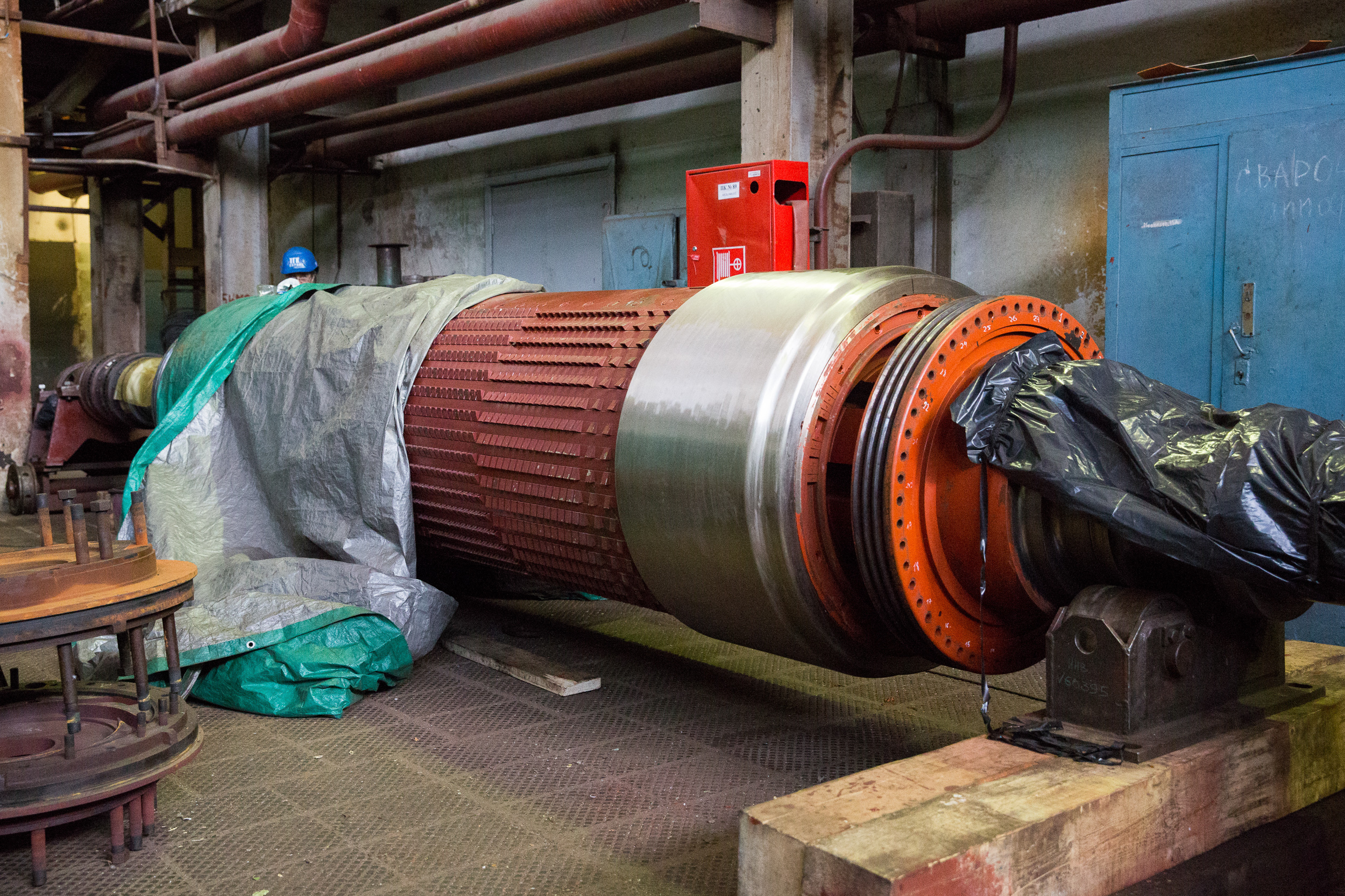 The generator rotor in the repair area is carefully covered, and workers examine each element